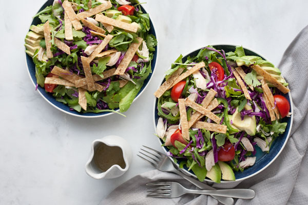 Avocado and Chicken Tortilla Salad | BourbonandHoney.com -- This Avocado and Chicken Tortilla Salad is piled with avocado, spicy jalapeño, crunchy tortilla strips and a bright lime dressing for a hearty weeknight salad.