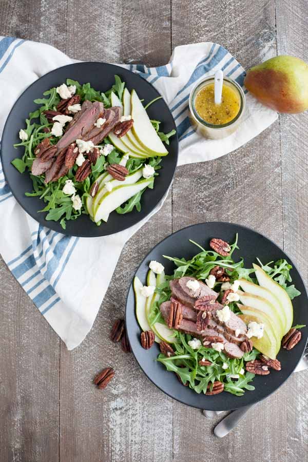 Arugula Flank Steak Salad with Pears and Blue Cheese | BourbonandHoney.com -- Filling, savory and delicious, this Flank Steak Salad recipe is topped with fresh pears, toasted pecans and lots of blue cheese and perfect for lunch or dinner!