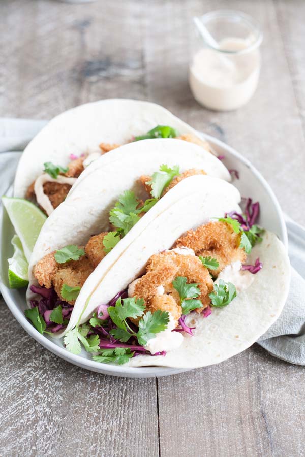 Coconut Shrimp Tacos with Cilantro Cabbage Slaw | BourbonandHoney.com -- Crispy, crunchy and totally delicious, these Coconut Shrimp Tacos are stuffed with cilantro cabbage slaw and a drizzle of spicy aioli.