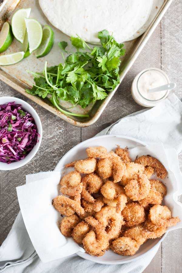 Coconut Shrimp Tacos with Cilantro Cabbage Slaw | BourbonandHoney.com -- Crispy, crunchy and totally delicious, these Coconut Shrimp Tacos are stuffed with cilantro cabbage slaw and a drizzle of spicy aioli.