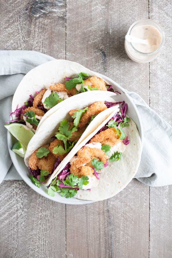 Coconut Shrimp Tacos with Cilantro Cabbage Slaw | BourbonandHoney.com -- Crispy, crunchy and totally delicious, these Coconut Shrimp Tacos are stuffed with cilantro cabbage slaw and a drizzle of spicy aioli.