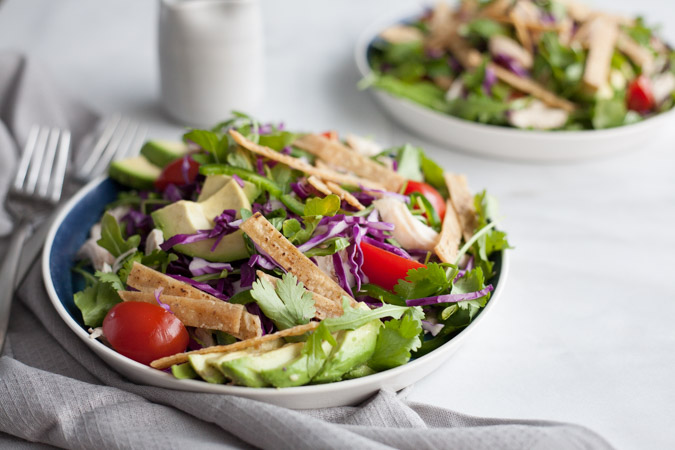 Avocado and Chicken Tortilla Salad | BourbonandHoney.com -- This Avocado and Chicken Tortilla Salad is piled with avocado, spicy jalapeño, crunchy tortilla strips and a bright lime dressing for a hearty weeknight salad.