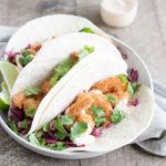 Coconut Shrimp Tacos with Cilantro Cabbage Slaw | BourbonandHoney.com -- Crispy, crunchy and totally delicious, these Coconut Shrimp Tacos are stuffed with cilantro cabbage slaw and a drizzle of spicy aioli.