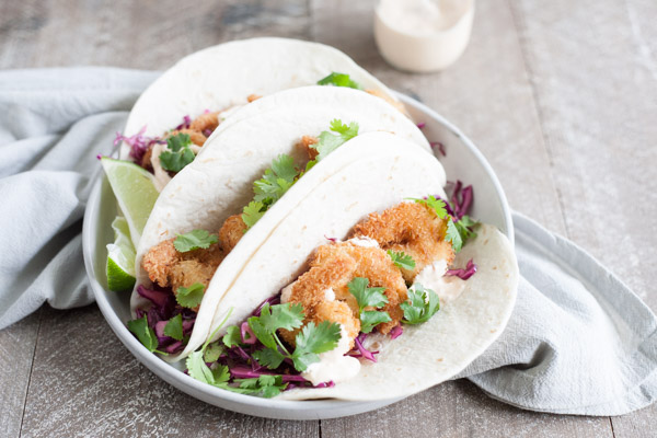 Coconut Shrimp Tacos with Cilantro Cabbage Slaw | BourbonandHoney.com -- Crispy, crunchy and totally delicious, these Coconut Shrimp Tacos are stuffed with cilantro cabbage slaw and a drizzle of spicy aioli.